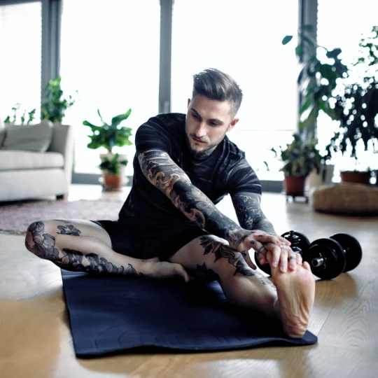 Mann mit Tattoos trainiert zuhause